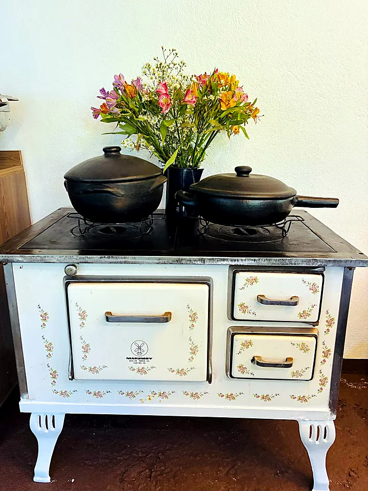 Fogão esmaltado antigo, com panelas de barro e um buquê de flores, no Rancho Santa Fé